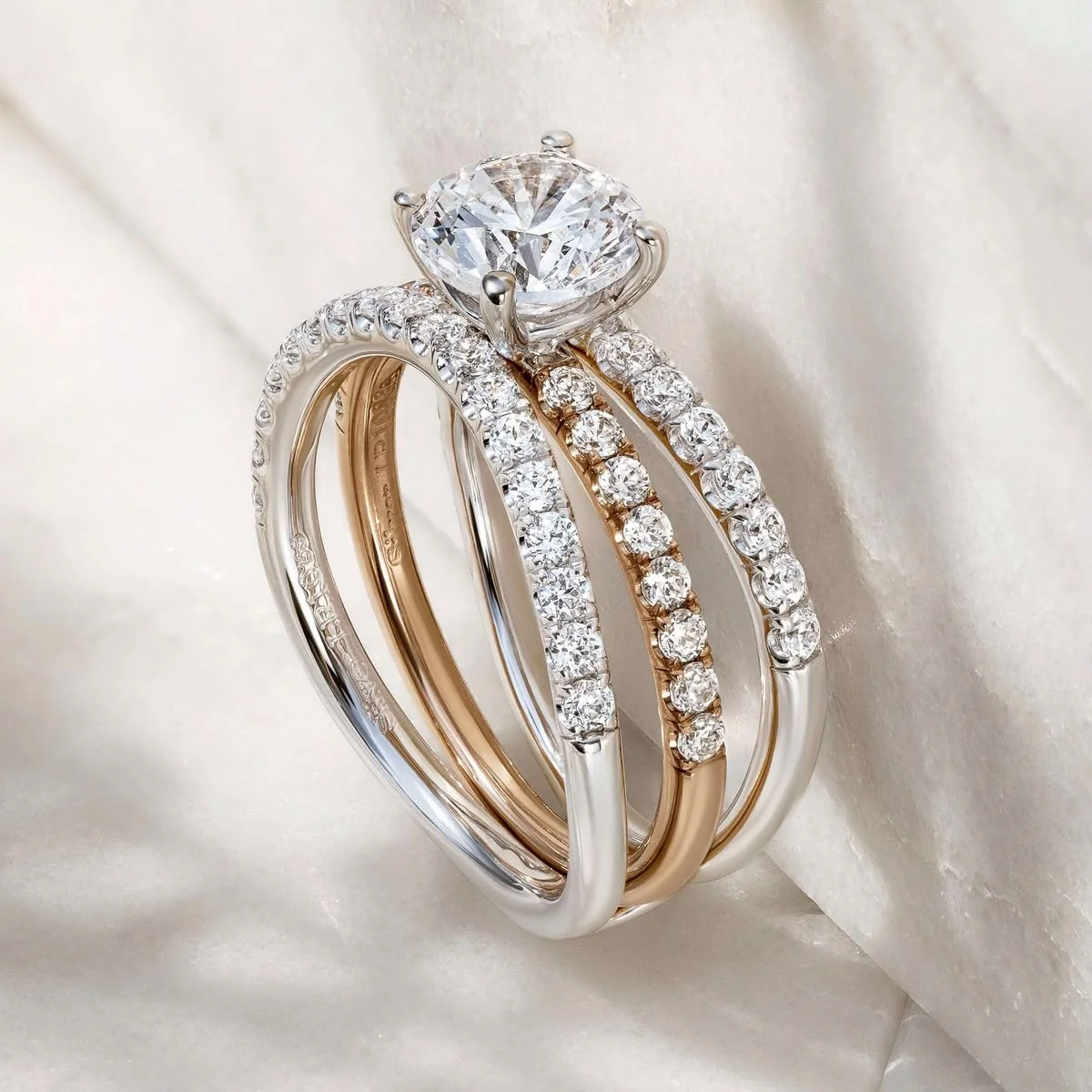 A solitaire ring and diamond bands arranged on white satin